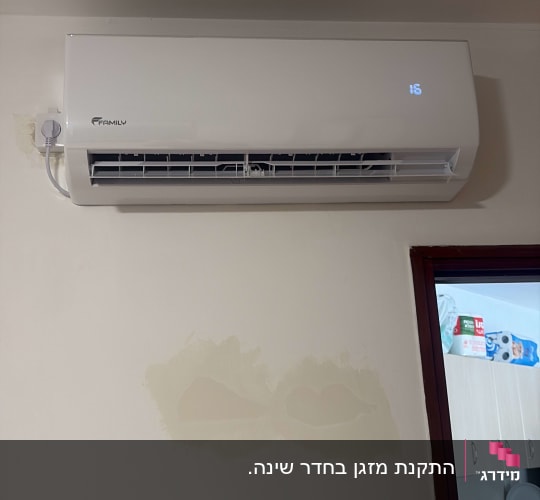 מזגן מותקן על קיר בחדר עם מטבח ברקע